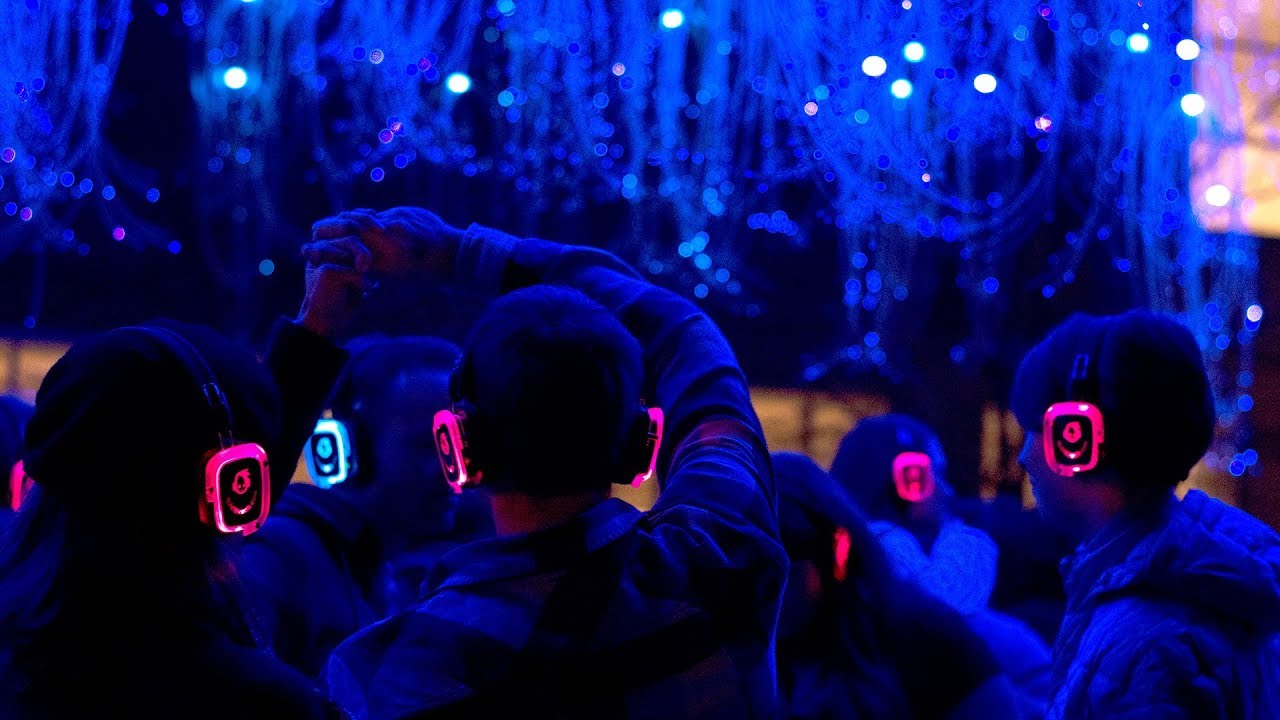 a group of people attend a silent disco wearing light up headphones
