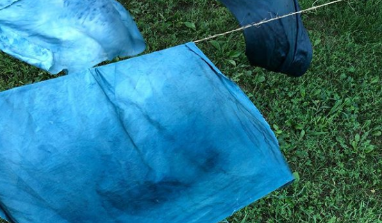 blue dyed fabric drying on a clothesline over grass