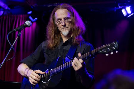 Pat Wictor plays guitar on a dark stage