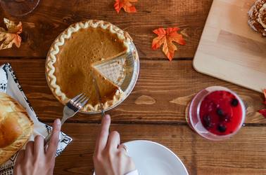 Pumpkin Pie being cut into slices on wooden table